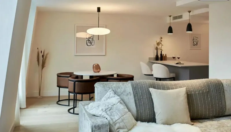 Modern Leven Manchester living room with beige sofa, round dining table, pendant lights, and kitchen bar.