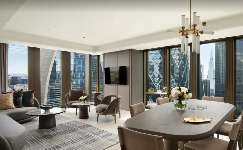 Luxurious Pan Pacific London suite with city skyline views, chandelier, plush seating, dining table, and flowers.