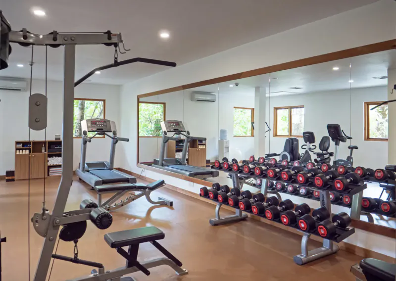Spacious gym at Mirihi Island Resort with treadmills, dumbbells, weight rack, and mirrors