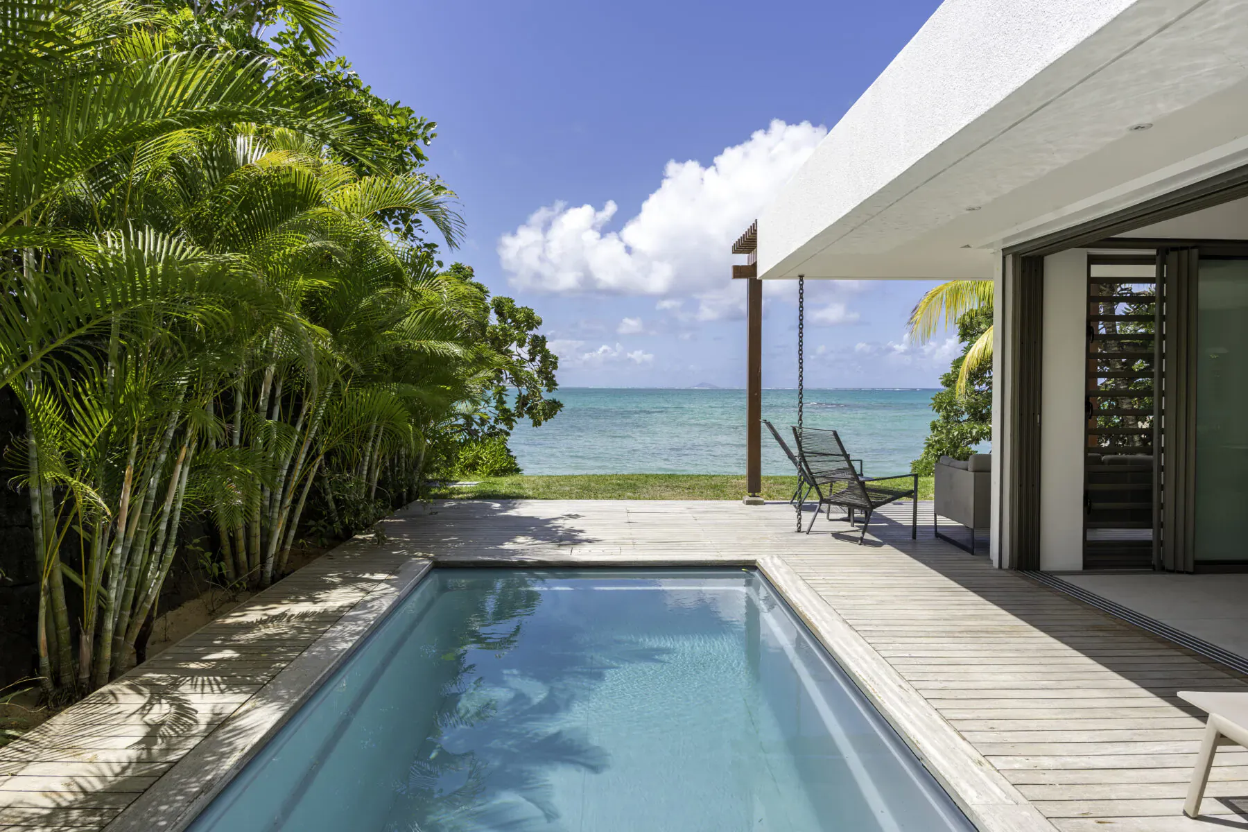 Villa Sapphire infinity pool on wooden deck with beach view, palm trees, and lounge chairs, Belle Mare Mauritius