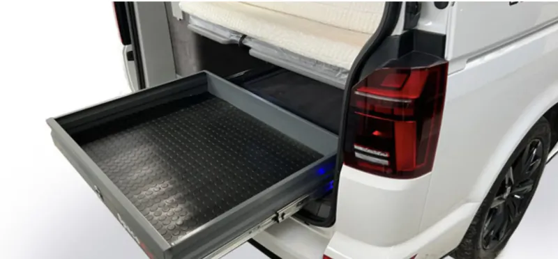 White campervan with black pull-out storage drawer extended from rear, luxury accessory