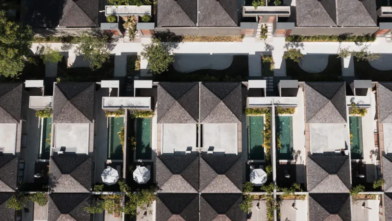 Aerial view of Cocana Resort in Gili Trawangan: row of modern villas with private green pools and umbrellas.