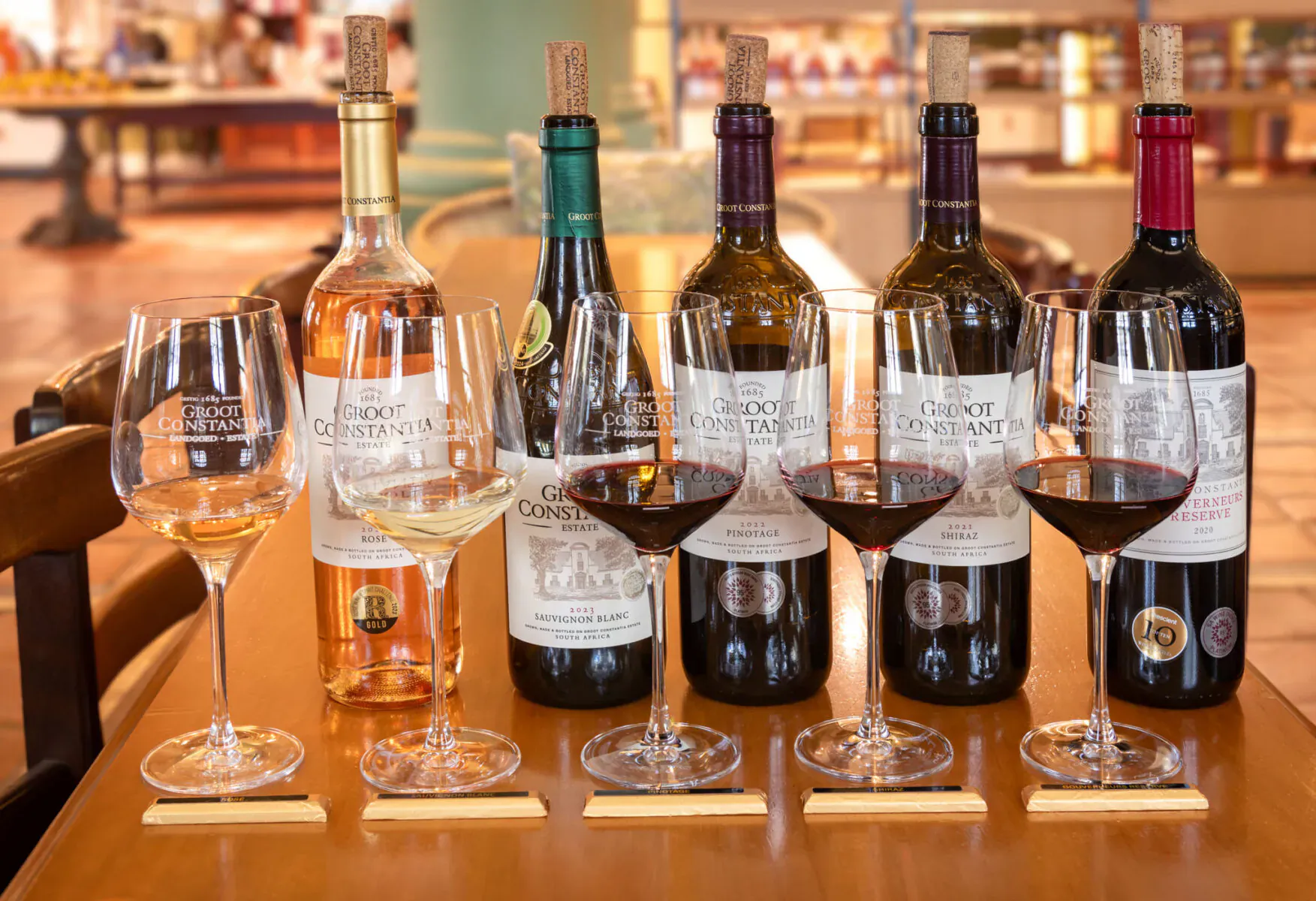 Groot Constantia wine tasting setup with white, rosé, and red wines in glasses on wooden table