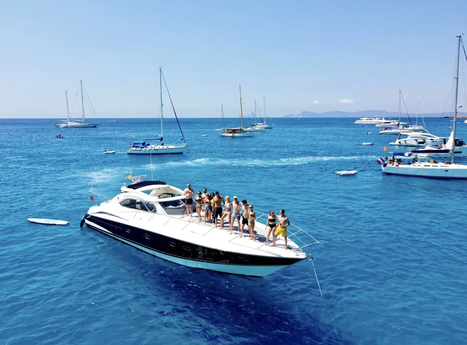 Group of women standing on white luxury yacht cruising in clear blue Croatian sea amid sailboats and mountains