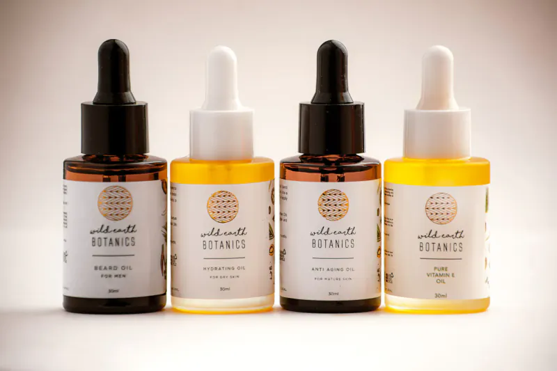 Wild Earth Botanics: four essential oil bottles labeled Beard Oil, Hydrator, Pure Oil, Body Oil on white background.