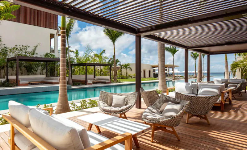 Outdoor terrace at Silversands Grenada with pool, palm trees, lounge chairs under shaded pergola