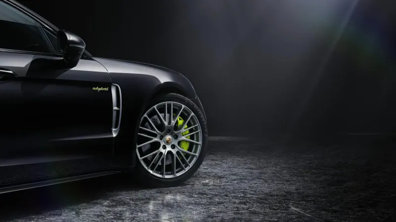 Black Porsche Panamera Platinum Edition side view, green brake calipers, dark studio with spotlight