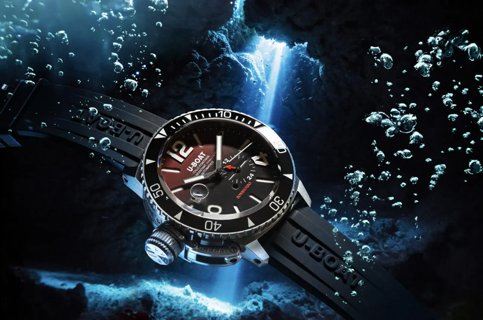 U-Boat Sommerso 46mm dive watch with black rubber strap, displayed underwater amid blue bubbles and light rays.