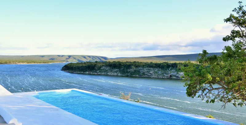 Infinity pool overlooking serene lake and lush green cliffs at De Hoop Preserve