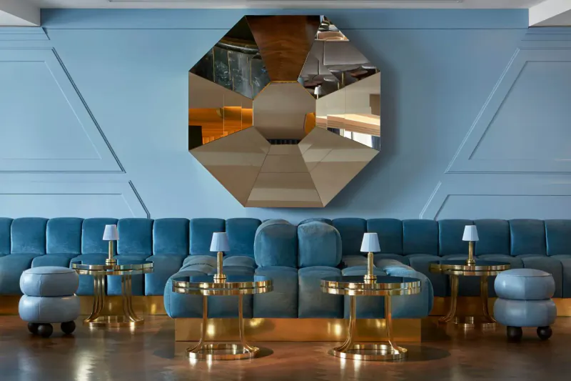 Sea Containers London spa: octagonal gold mirror on blue wall above blue velvet sofa, gold tables, lamps, poufs
