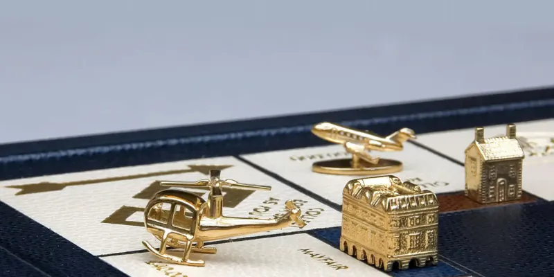 Luxury gold Monopoly tokens: airplane, helicopter, house, and hotel on board