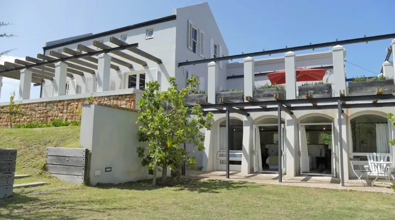 White South Hill Vineyards house in Elgin Valley with pergola, red banners, patio, and garden on hillside