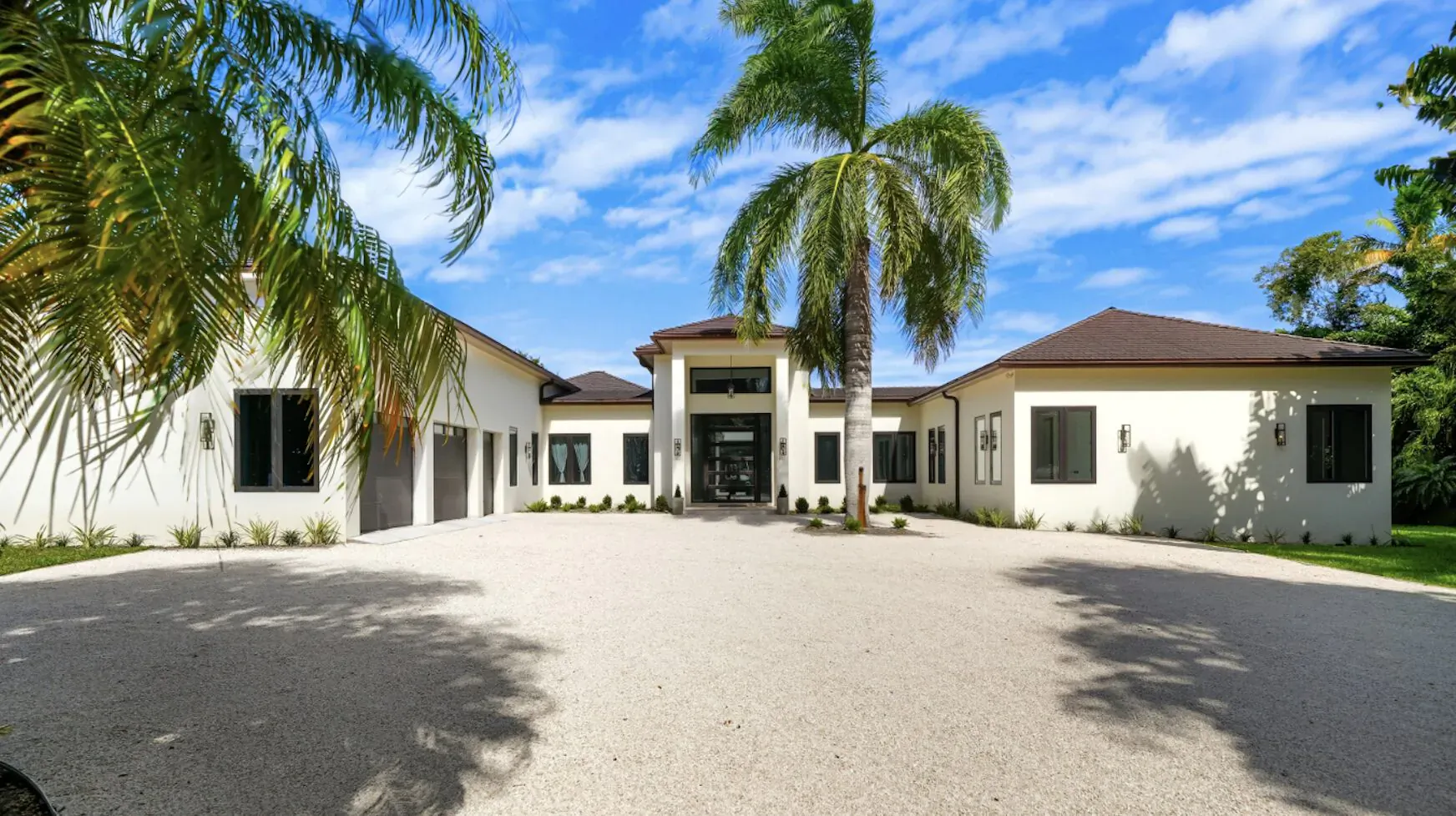 Modern white luxury mansion with palm trees and driveway at Lyford Cay, Bahamas