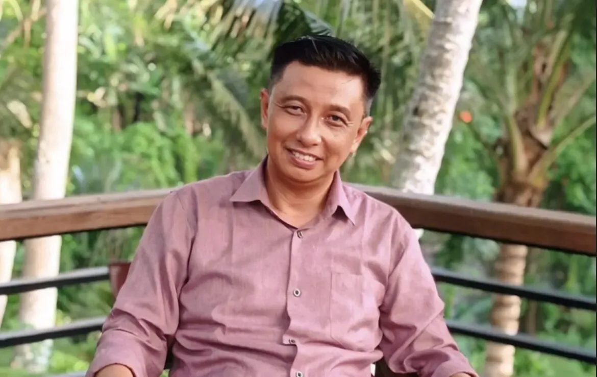 Putu, GM of Kayumanis Ubud Bali, smiling in pink shirt on wooden balcony amid lush tropical greenery