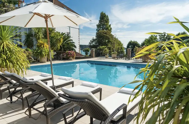 Tranquil infinity pool at St. Brelade’s Bay Hotel, Jersey, with lounge chairs, umbrellas, palms, and bay view.