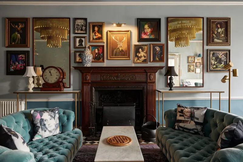 Elegant Brasserie Beau Bath lounge with turquoise velvet sofas, ornate fireplace, eclectic art gallery walls, and brass lamps.
