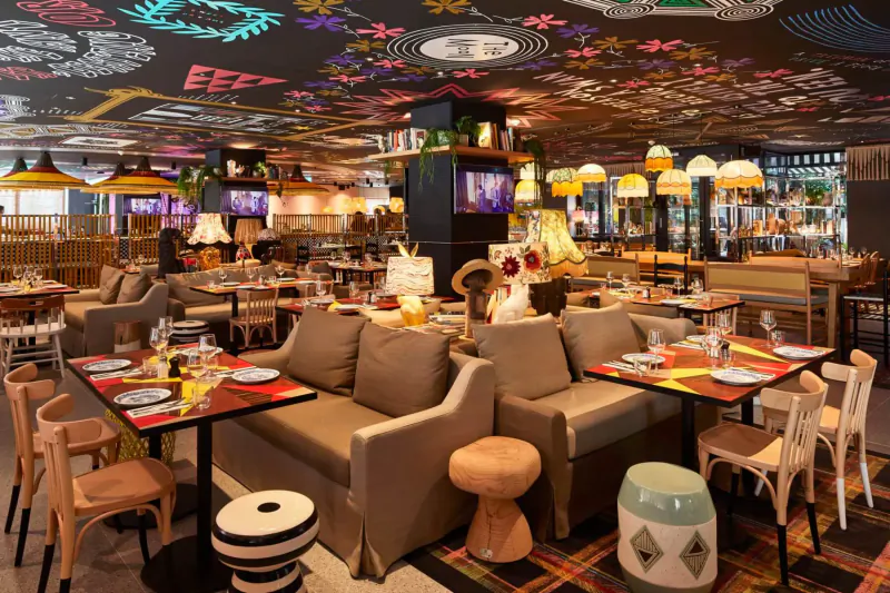 Vibrant Halloween-themed restaurant interior at Mama London with ghoulish decor, colorful lamps, eclectic seating, and tables.