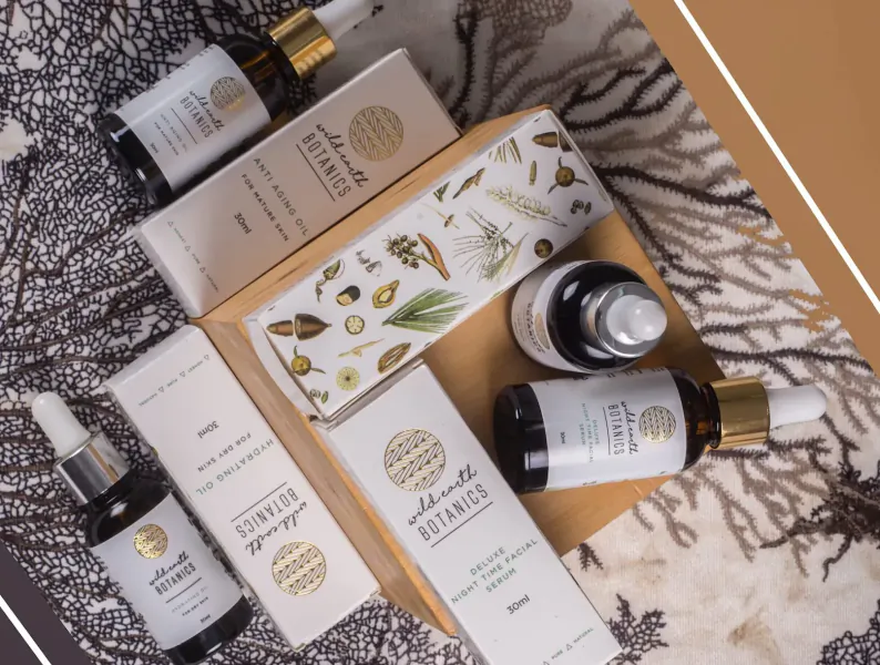 Wild Earth Botanics natural oils, serums, and boxes with botanical illustrations on seaweed backdrop