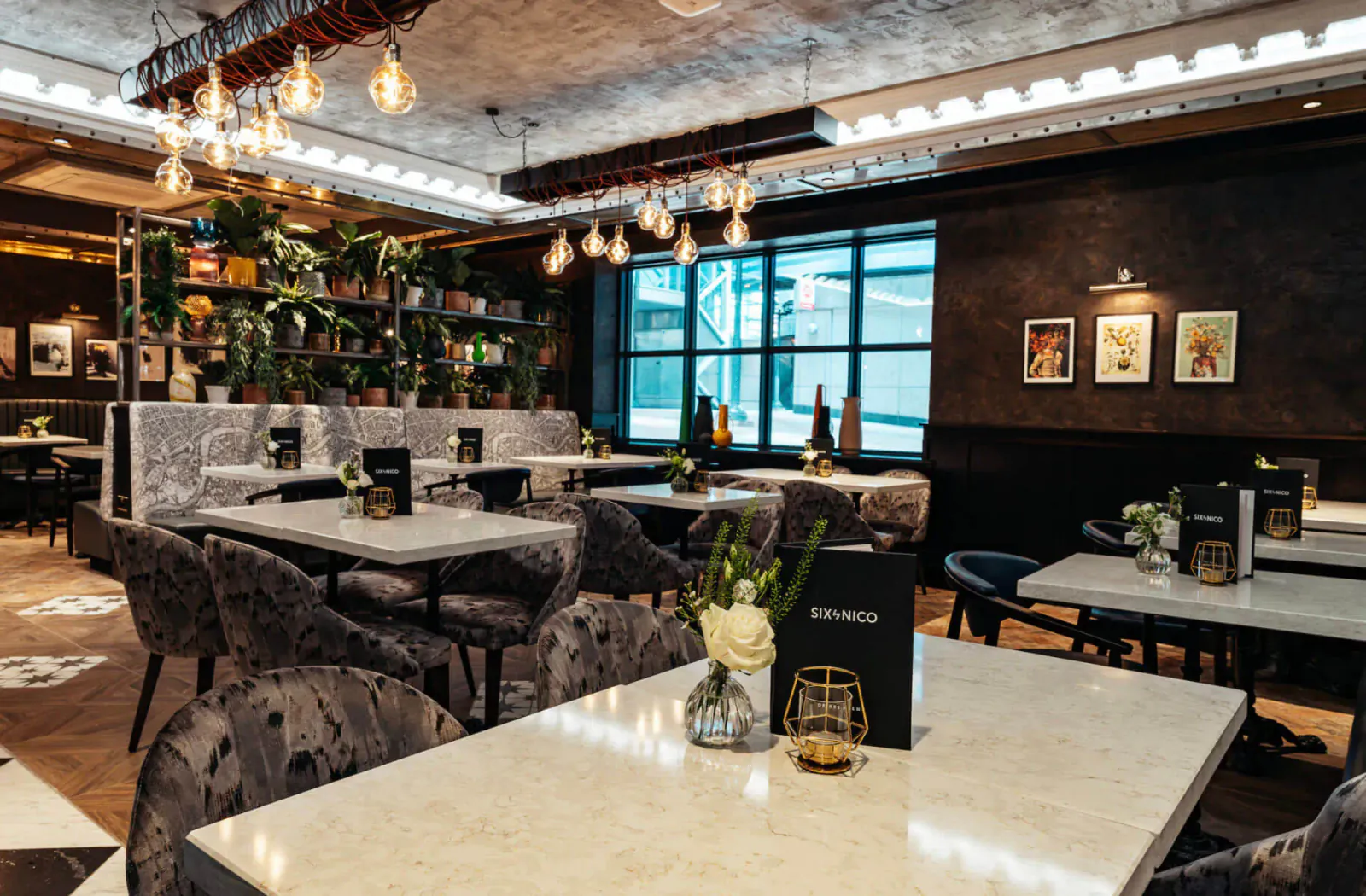 Elegant Six by Nico restaurant interior in Canary Wharf with marble tables, velvet chairs, pendant lights, plants, and window views.