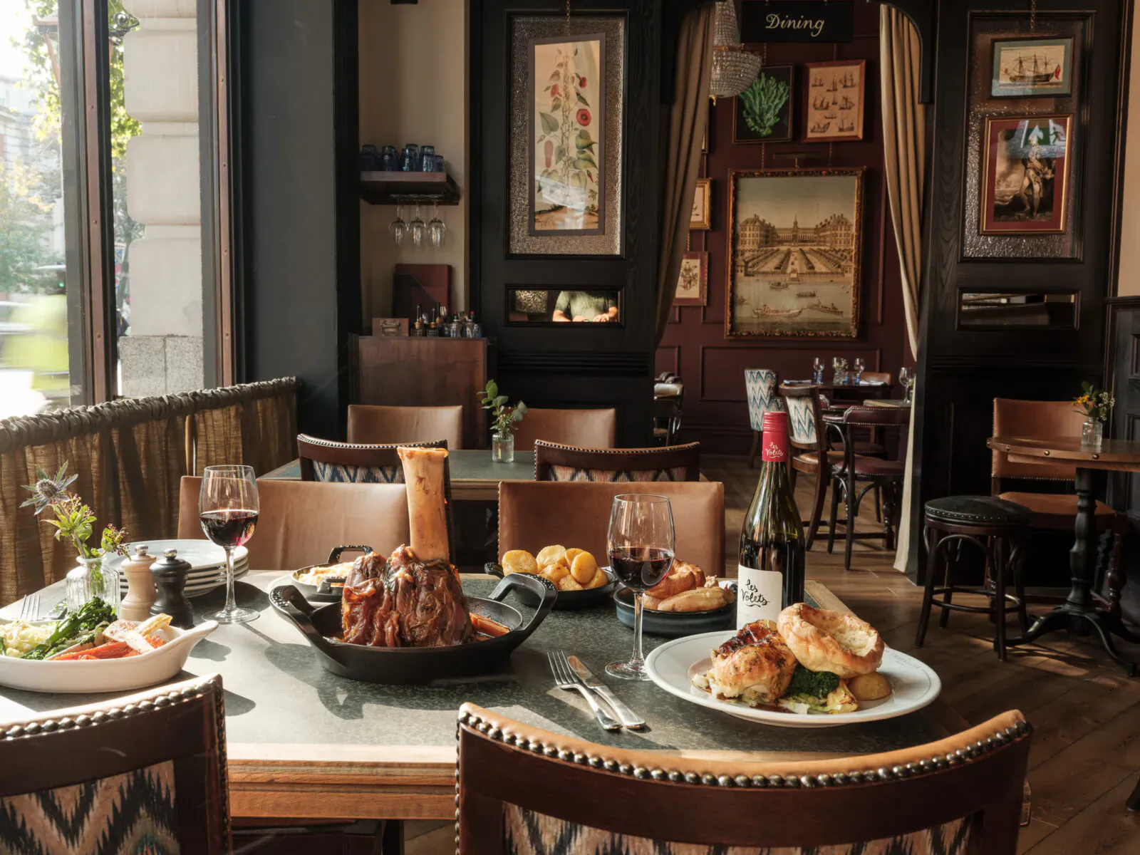 Elegant dining table at The Trafalgar Public House with braised meat, fish dish, wine, and art-filled interior