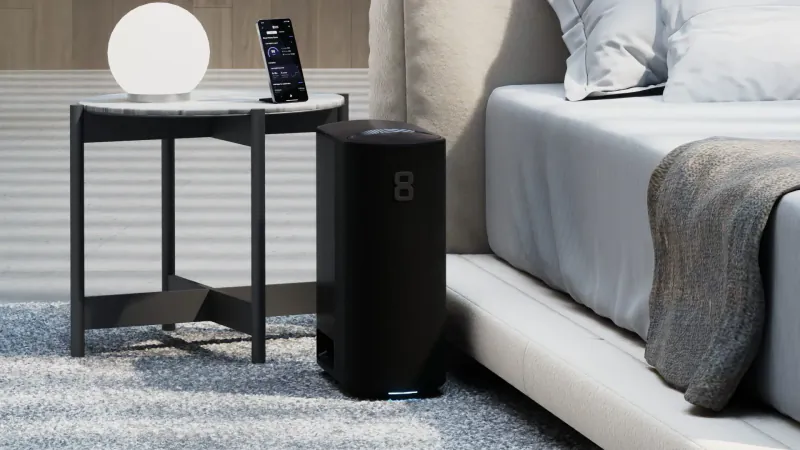 Modern bedroom with Eight Sleep black smart mattress base beside bed, smartphone and orb lamp on round table