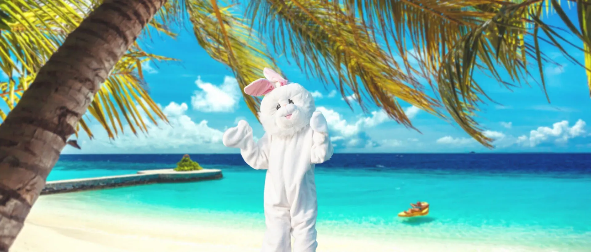 White bunny mascot posing with arms raised on tropical beach at Lily Beach Resort, palm trees and turquoise ocean backdrop