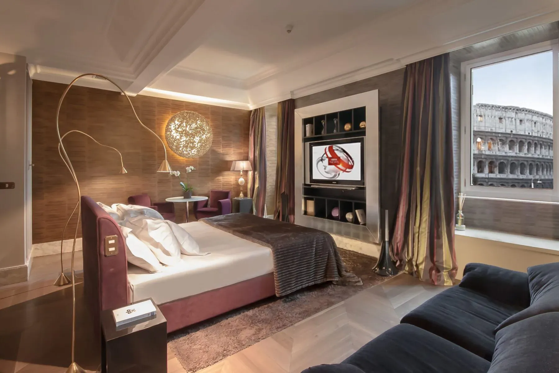 Luxury Rome hotel room with Colosseum view, king bed, TV showing red crab, plush seating