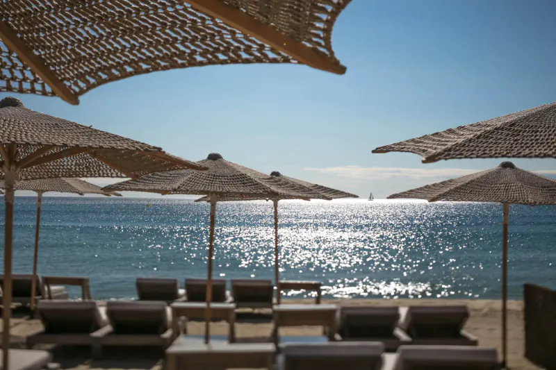 Luxury beach club at Hôtel Byblos St Tropez: thatched umbrellas, loungers, sparkling sea under blue sky