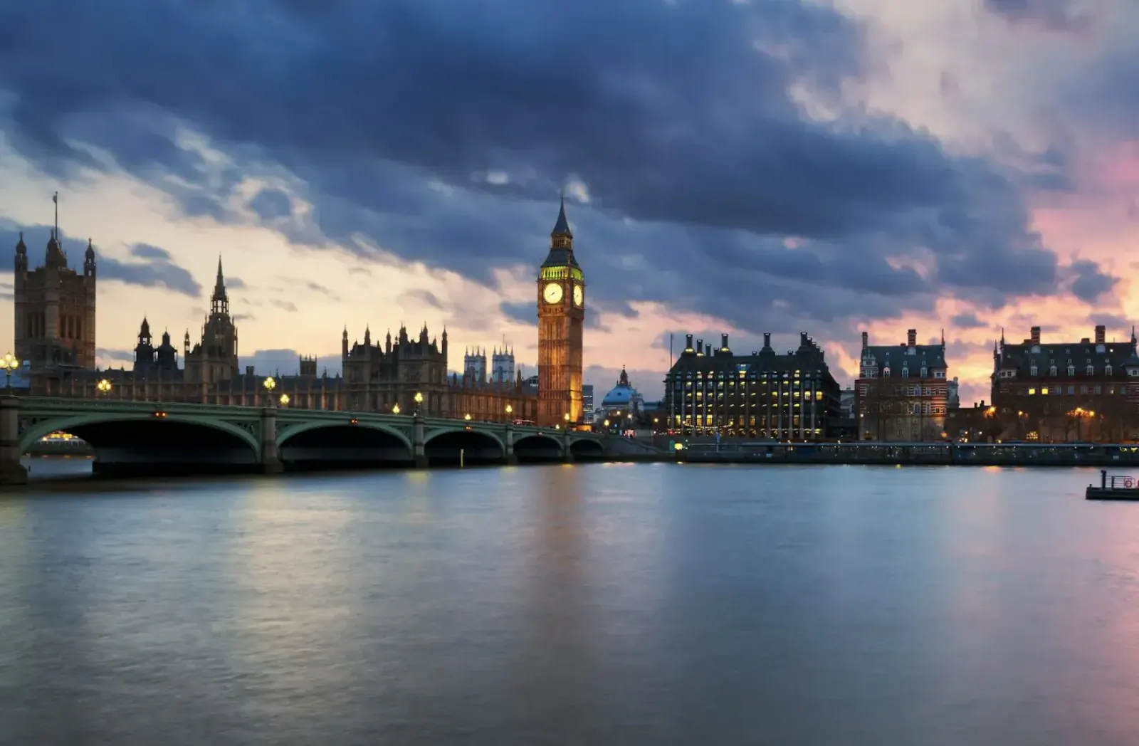 Twilight view of Big Ben and Houses of Parliament across River Thames with bridges under dramatic purple-pink clouds