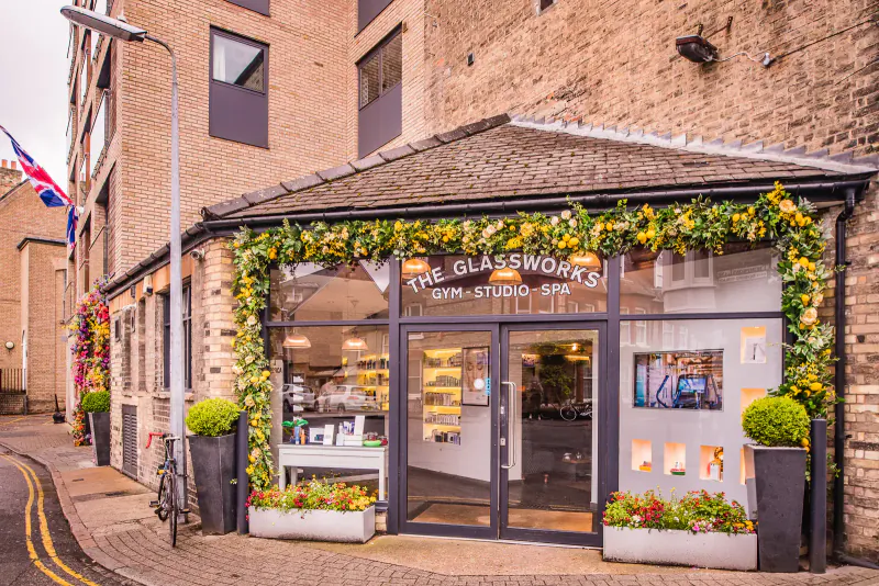 The Glassworks shopfront at Varsity Hotel & Spa, brick building with garland, Union Jack flag, plants, and glass display windows.
