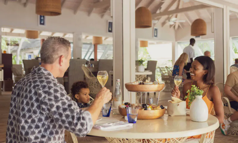 Family toasting with champagne flutes over charcuterie at Catherine’s Café Sur La Plage in Antigua.