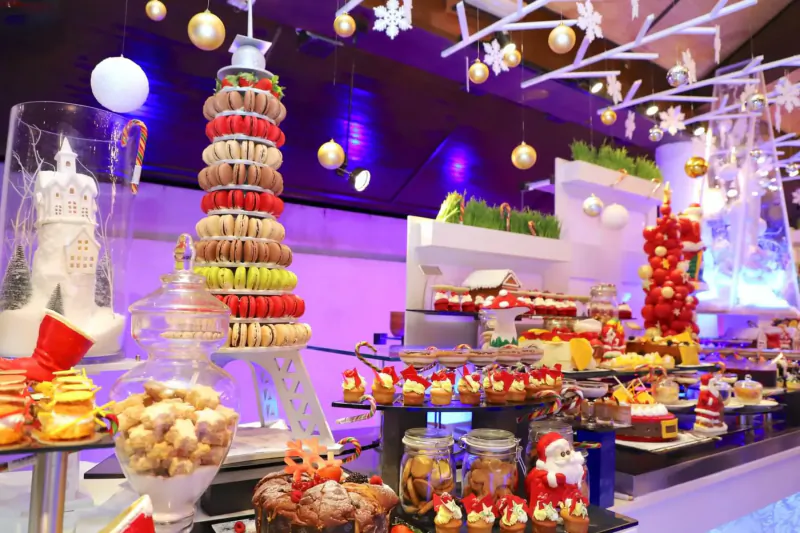 Festive Christmas dessert buffet at Lily Beach Resort with macaron Eiffel Tower, Santa treats, candy canes, and gold ornaments.