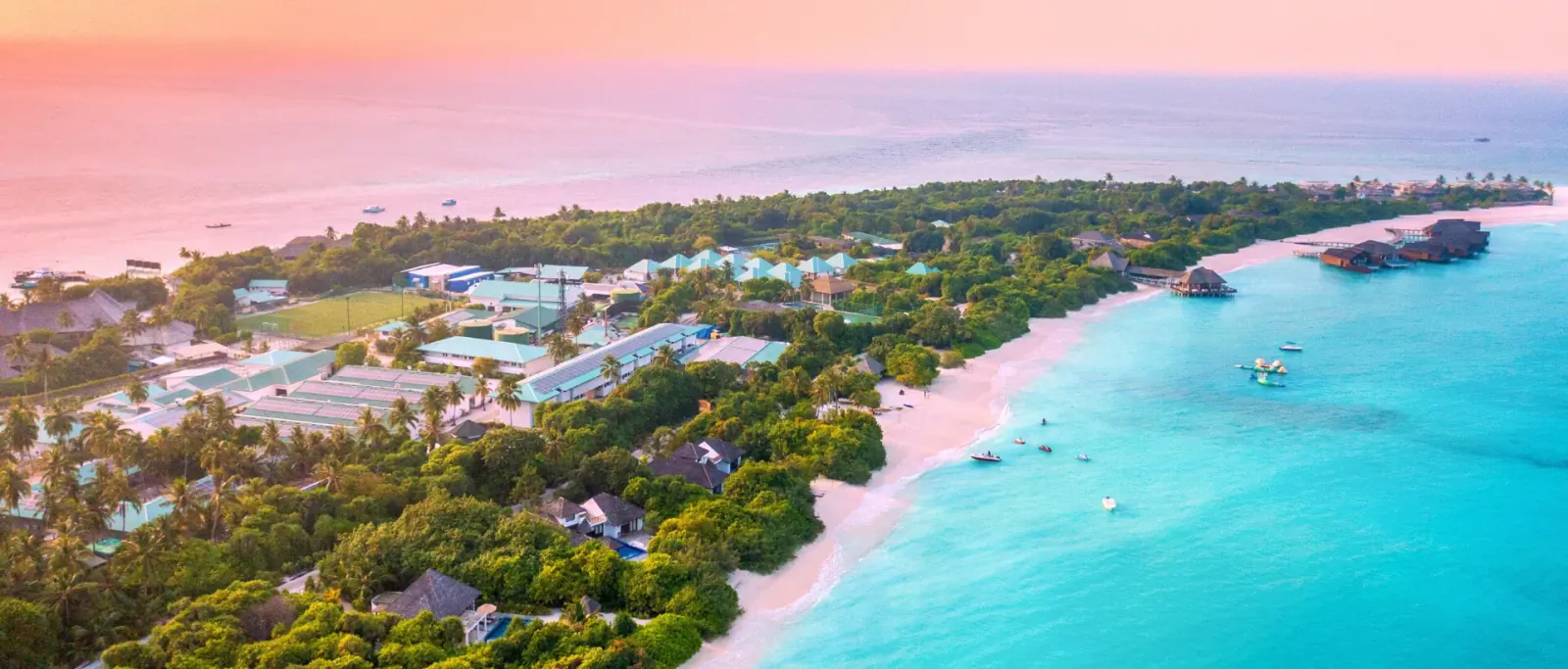 Aerial view of Hideaway romantic resort on tropical island with white beach, turquoise lagoon, lush greenery at sunset