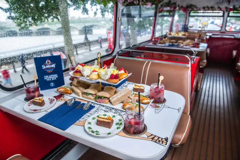 Afternoon tea on Slingsby Gin vintage red double-decker bus with sandwiches, cakes, and gin drinks by the Thames.