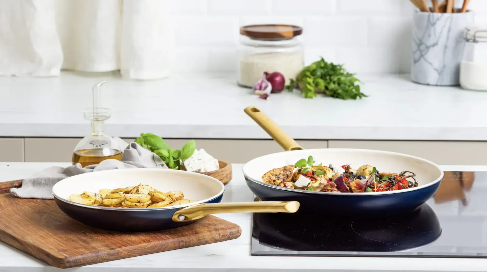 Padova frying pan collection: navy pans with pasta and tomato veggie dish on kitchen counter.