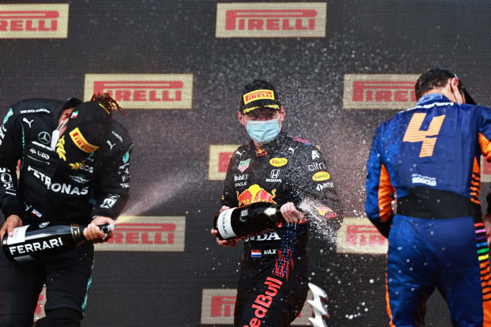 F1 podium: Mercedes driver #44 sprays champagne on Red Bull #33 and McLaren #4 against Pirelli backdrop