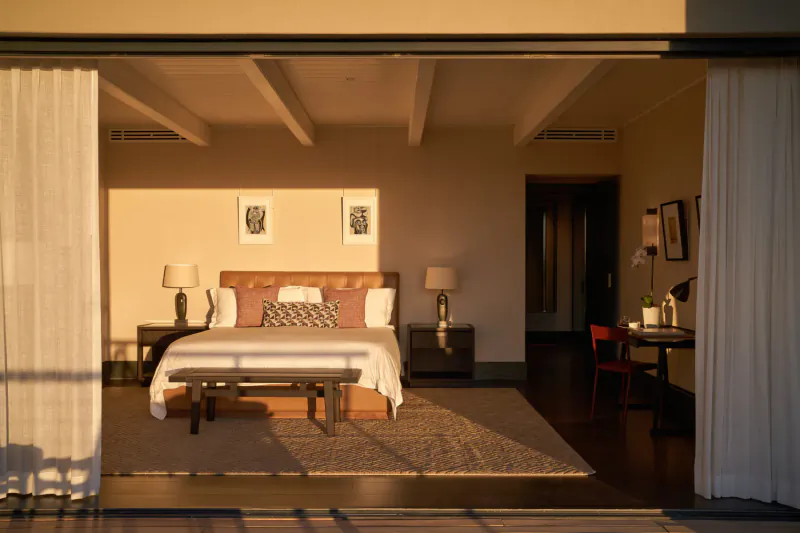 Luxurious bedroom at Delaire Graff Estate with king bed, open doors to terrace, warm sunset light