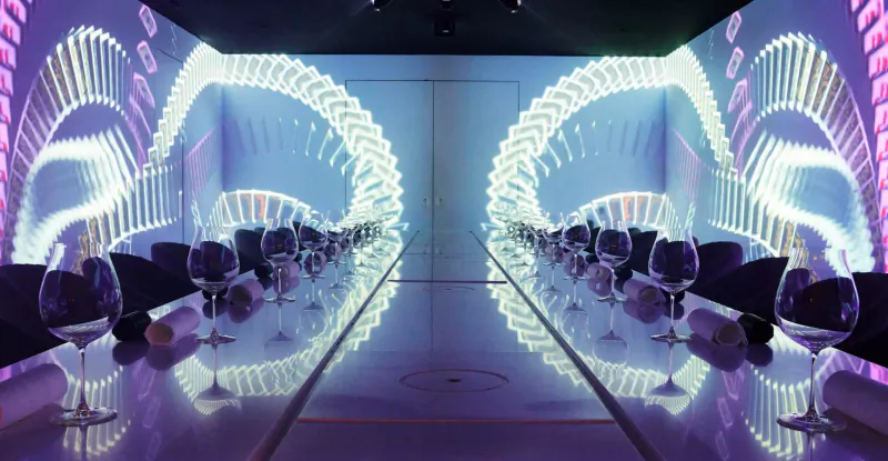 Symmetrical view of Monarch Theatre gallery: long table with wine glasses, mirrored floor, glowing arched LED walls.