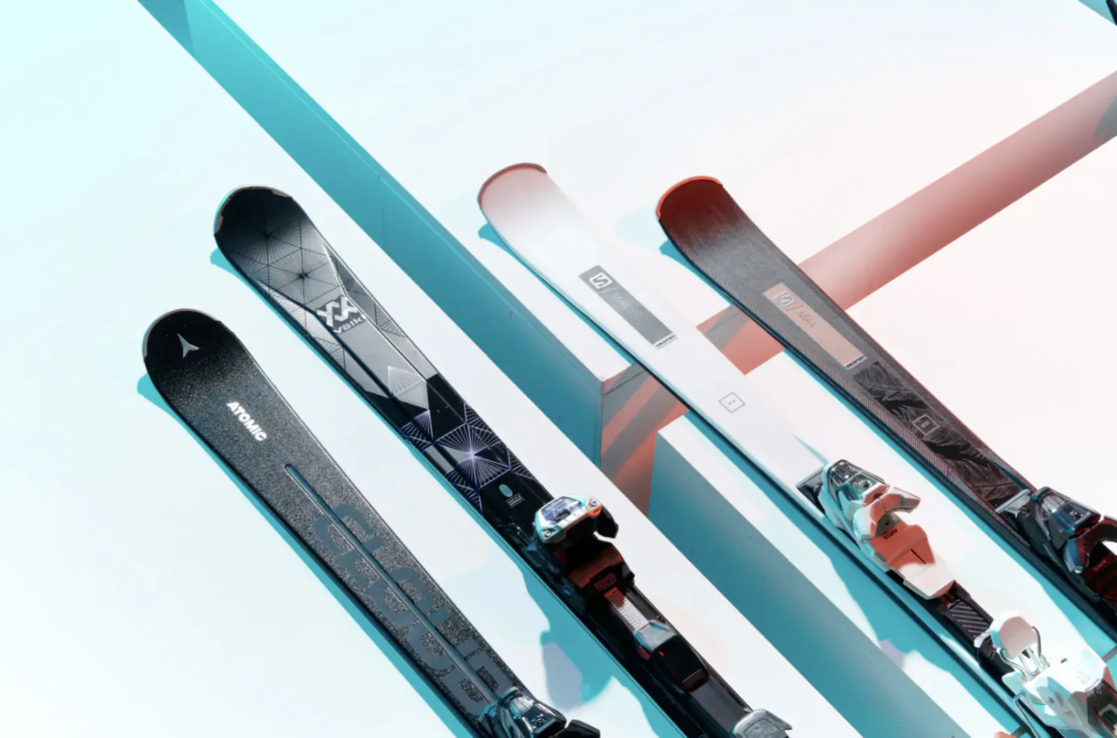 Several sleek skis with bindings arranged diagonally against a blue snowy background