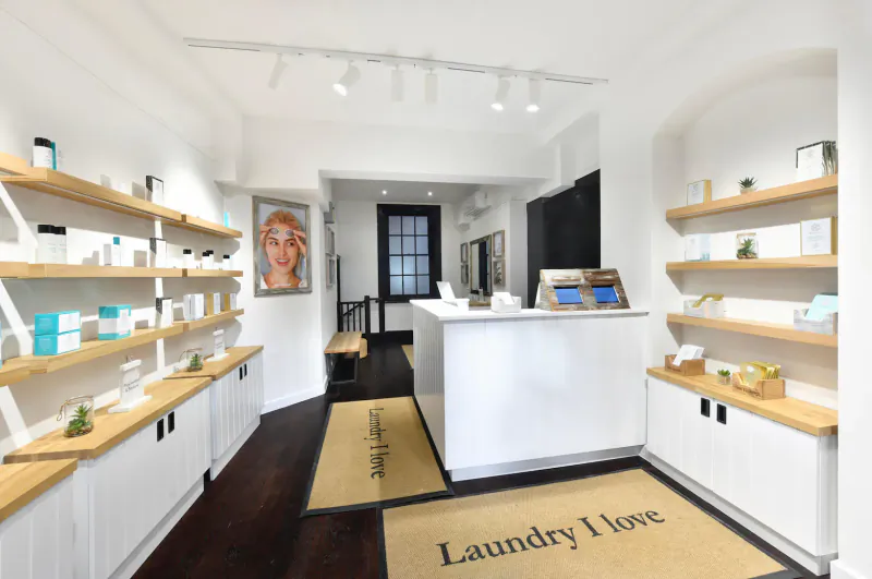 Laundry I Love laundry shop interior with white shelves of products, reception desk, and 'Laundry I Love' rug.