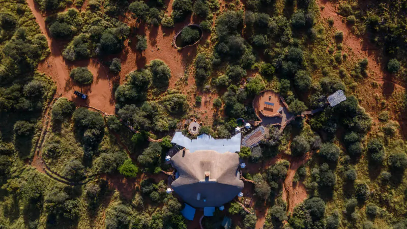 Aerial view of Tarkuni luxury tented camp and Star Bed at Tswalu, surrounded by red Kalahari scrubland.