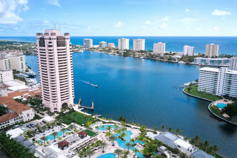 Aerial view of pink high-rise tower, luxury condos, pools, and waterways in Boca Raton, Florida.
