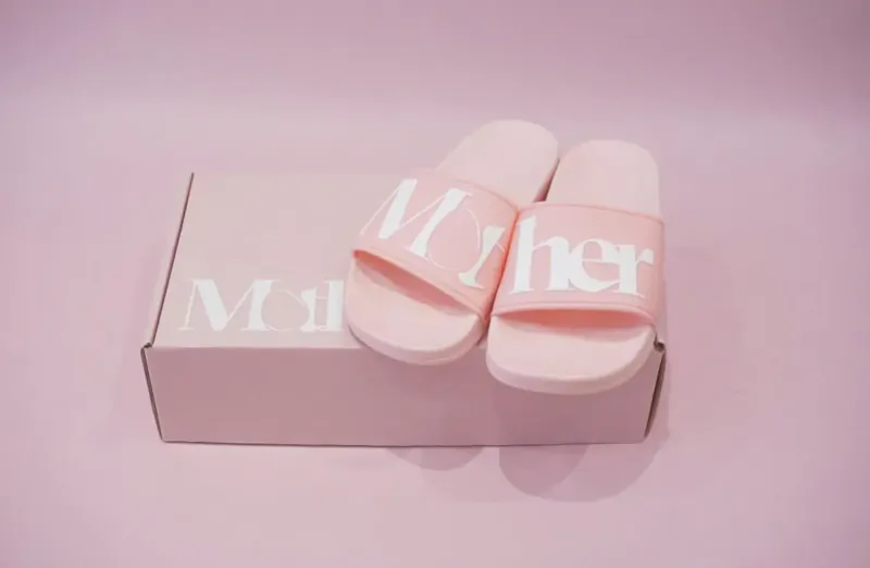 Pink 'MoTHER' flip-flops on matching pink box, freelance agency for mothers.