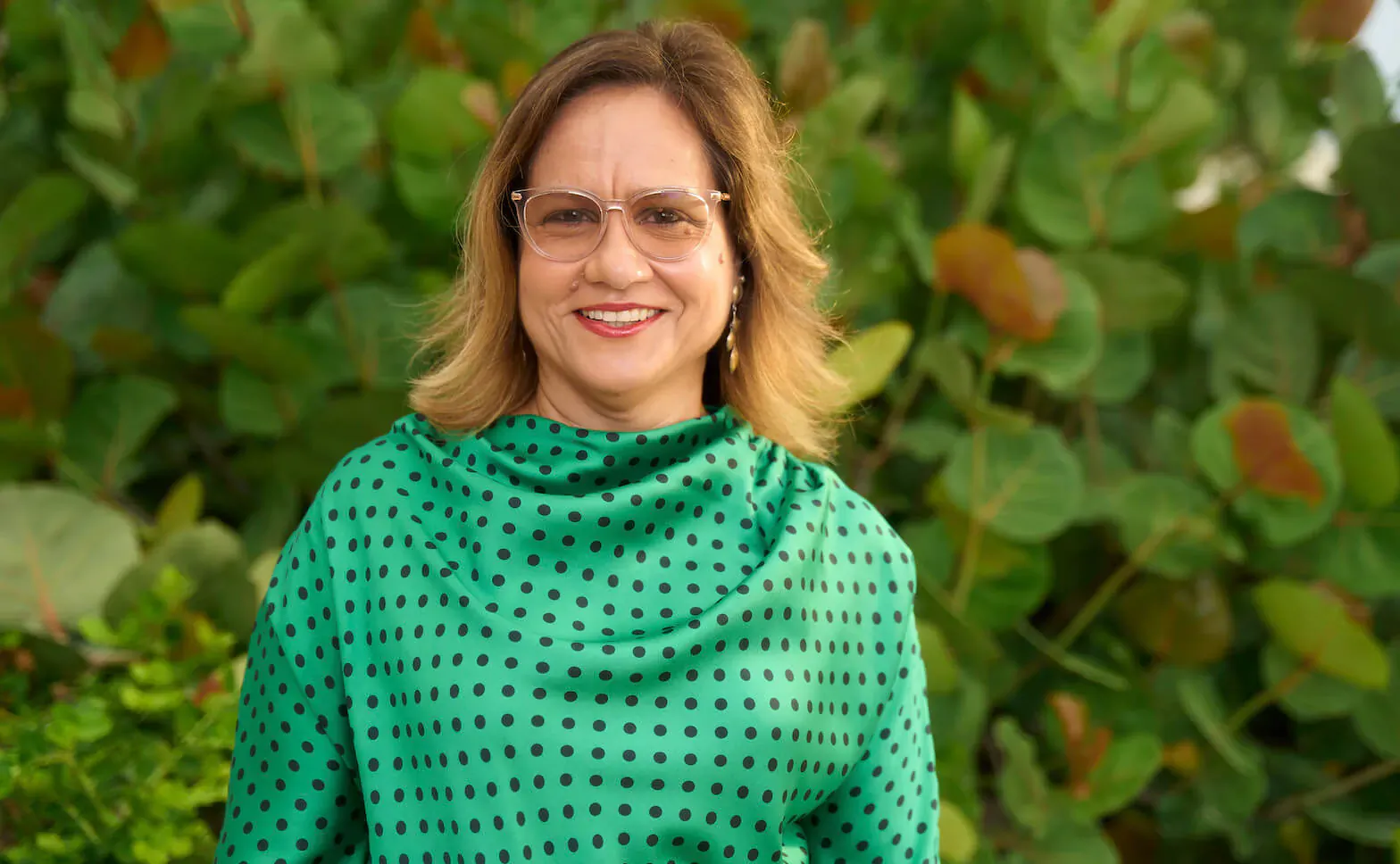 Patricia Affonso, CEO of Ocean Hotels Barbados, smiling in green polka-dot top against tropical green backdrop