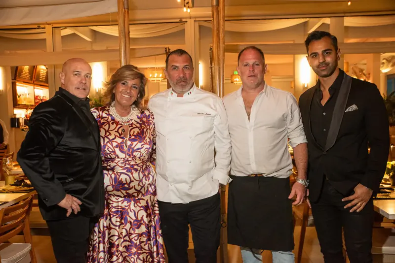 Pat Martin, pitmaster in chef whites, poses with three suited men and a woman in purple dress at South Beach Food festival.