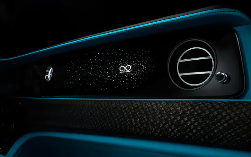 Close-up of Rolls-Royce Black Badge Ghost dashboard with infinity symbol illuminated on display and air vents.
