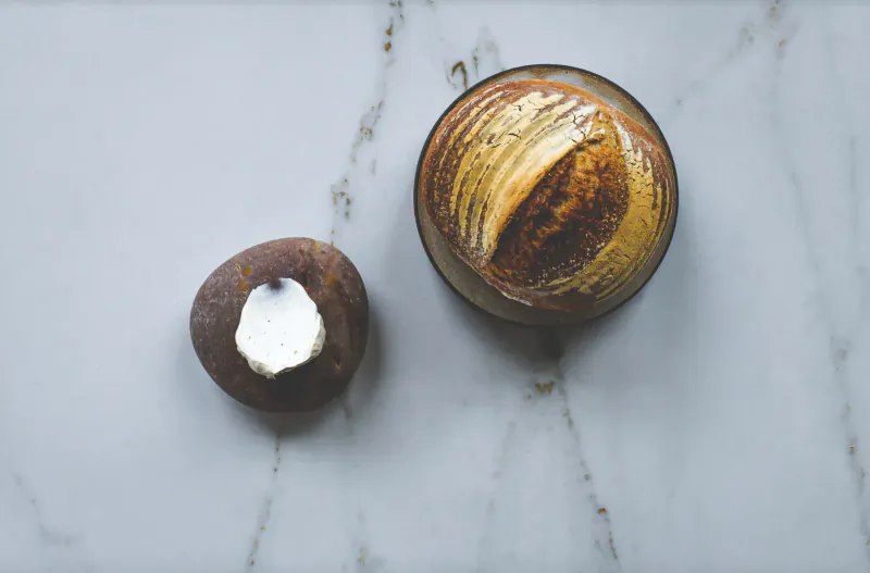Two gourmet pastries topped with white cream on a marble surface at fine dining venue