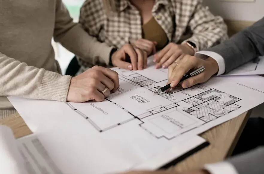 Professionals reviewing architectural house blueprints around a table