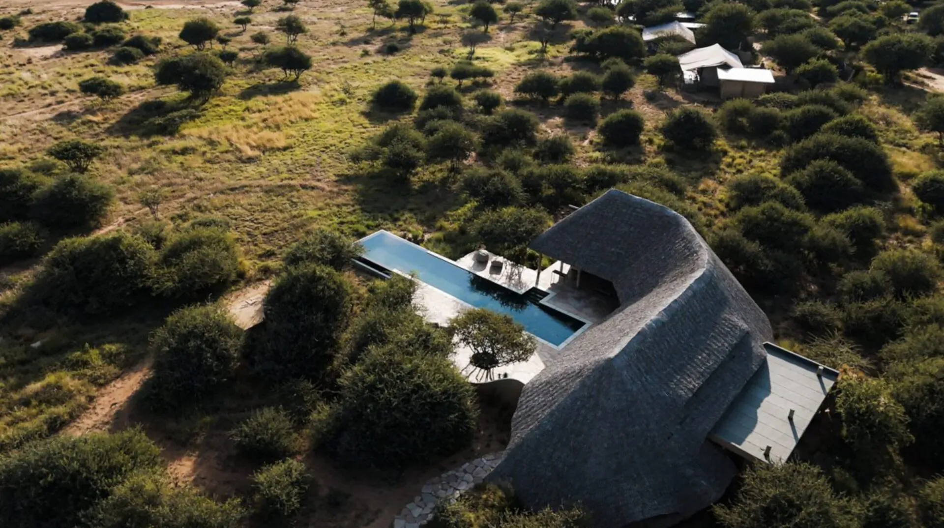 Aerial view of Ahnasa luxury lodge with infinity pool amid African savanna bushland