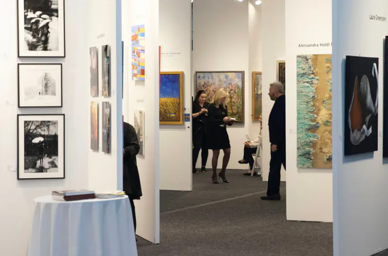 People viewing diverse paintings in modern art gallery at Artexpo Dallas